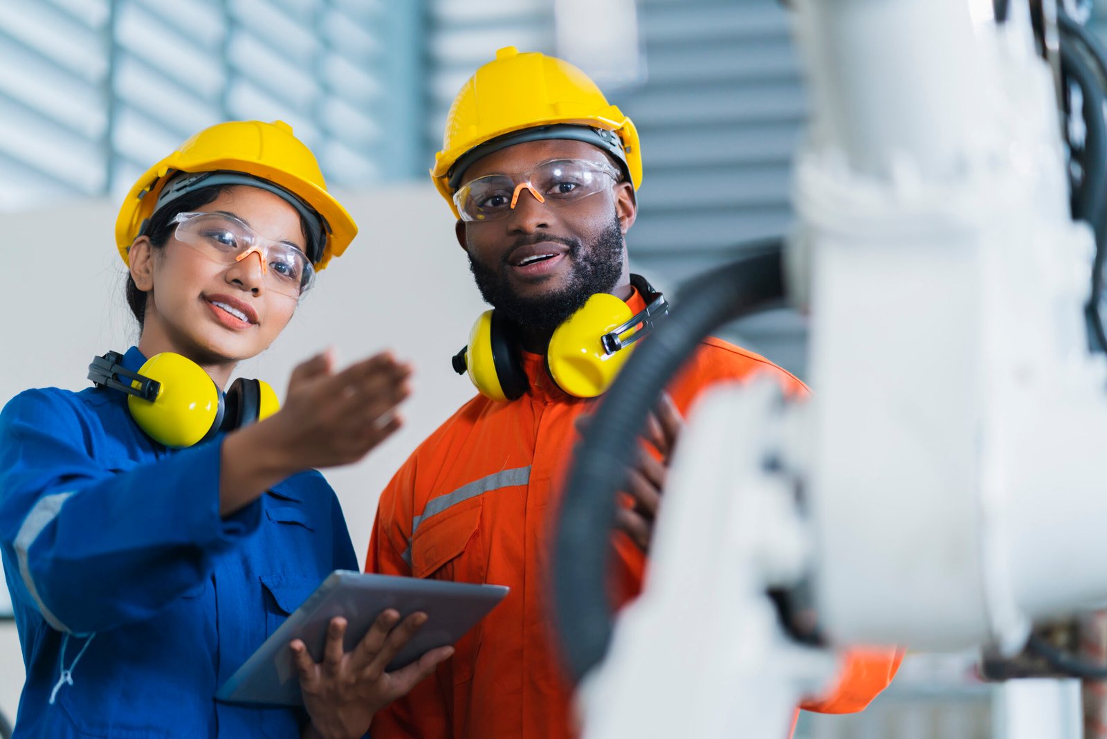 engineer cooperation male and female technician maintenance control relay robot arm system welding with tablet laptop to control quality operate process work heavy industry 4.0 manufacturing factory